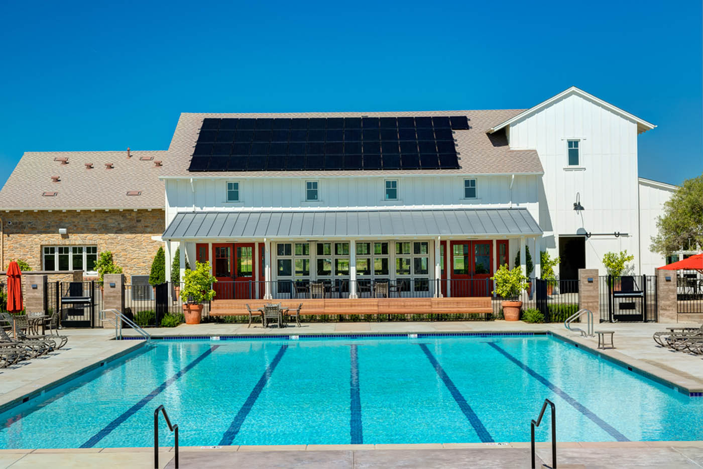 A large house with solar panels on the roof and a pool in the backyard.