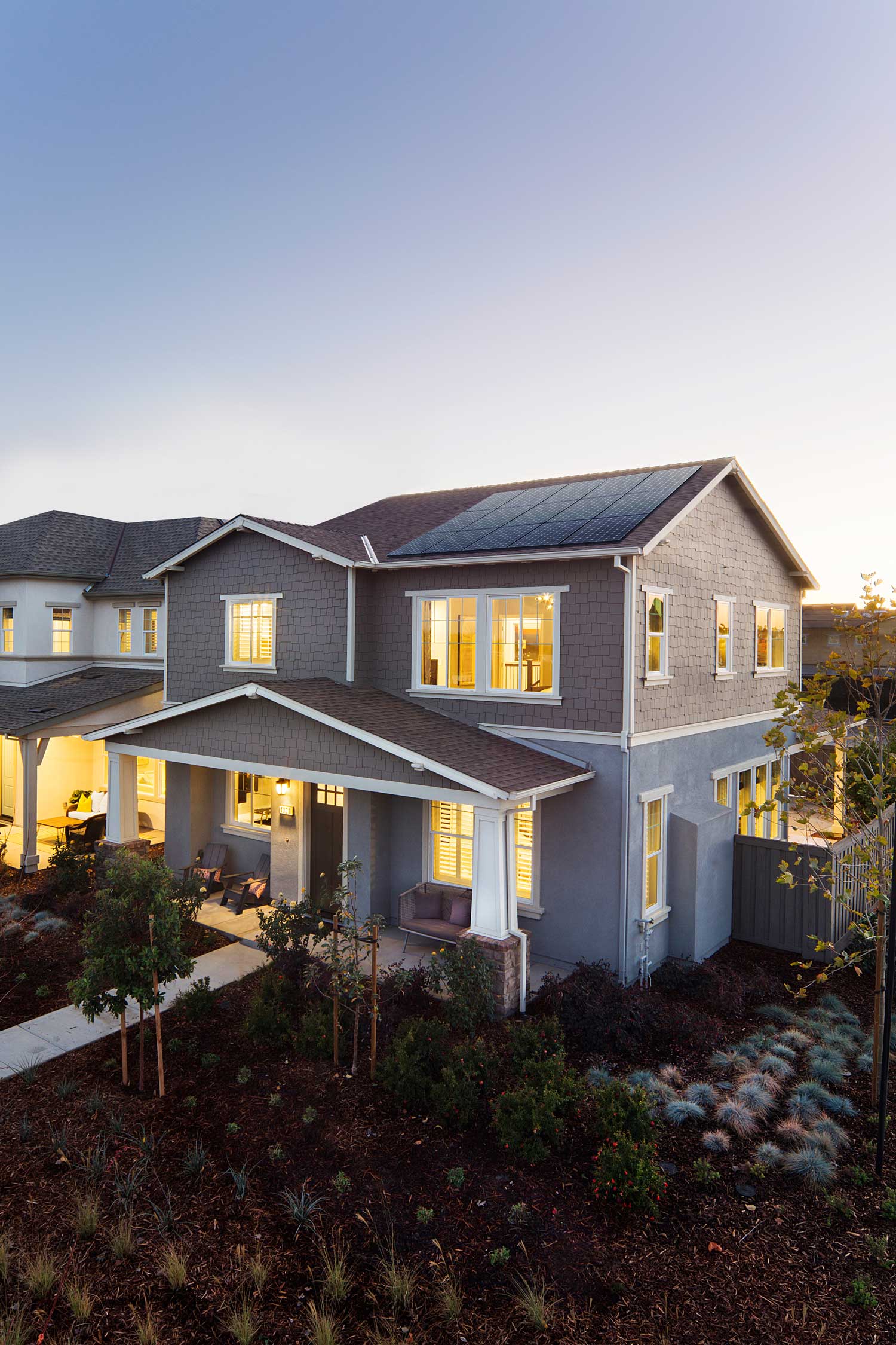 A grey house at dusk with lighting generating power from their solar panels.